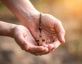 A close-up of two hands gently holding a small wooden cross pendant Royalty Free Stock Photo