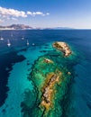 A reef in the ocean surounded by turquoise sea and moored luxury yachts. A beautiful Royalty Free Stock Photo