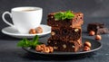 A stack of chocolate brownies with mint and hazelnuts on a dark background with cup Royalty Free Stock Photo