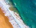 Aerial view of a beach with turquoise blue ocean waves gently rolling onto an orange sandy shore Royalty Free Stock Photo