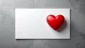A red, glossy heart-shaped object is placed on a white rectangular surface Royalty Free Stock Photo
