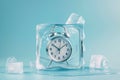 Alarm clock in ice cube, frozen time. Stopping the time concept, freeze time. Royalty Free Stock Photo