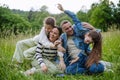 Beautfiul young family sitting in grass at meadow, enjoying together time.