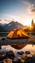 Camping tent by lake at sunrise with mountain backdrop and sun rays Royalty Free Stock Photo