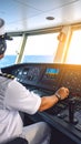 Captain navigating ship at sea, view from behind with control panel and sunny ocean Royalty Free Stock Photo