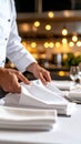 Chef arranging white napkins on a restaurant table, preparing for service. Royalty Free Stock Photo