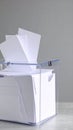 Clear acrylic ballot box filled with blank white papers for voting suggestions or anonymous surveys on a grey surface Royalty Free Stock Photo