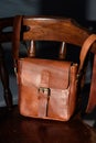 close-up photo of brown messanger leather bag on a wooden chair