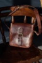 close-up photo of brown messanger leather bags on a wooden chair