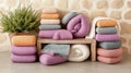 Soft, colorful blankets neatly stacked on a rustic wooden bench against a stone wall, AI Royalty Free Stock Photo