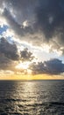 Dramatic sunset over ocean with clouds and sunlight reflecting on water surface Royalty Free Stock Photo