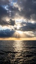Dramatic sunset over ocean with sun rays breaking through dark clouds Royalty Free Stock Photo