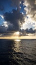 Dramatic sunset over ocean with sun rays breaking through dark storm clouds Royalty Free Stock Photo