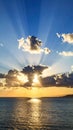 Dramatic sunset over the ocean with sun rays piercing through clouds Royalty Free Stock Photo