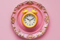 Empty plate with yellow alarm clock on pink background, intermittent fasting concept. Royalty Free Stock Photo