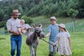 Farmer family walking with donkey on their farm. A gray mule as a farm animals at the family farm. Concept of