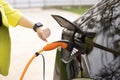 Female hands disconnects plug power cable. Unrecognizable woman unplugging electric car cable. Girl stopping charging