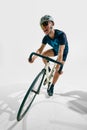 Full-length dynamic image of young man, professional cyclist in motion, training isolated on white background. Royalty Free Stock Photo
