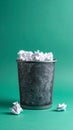 Full trash can with crumpled paper on green background Royalty Free Stock Photo