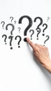 Hand pointing at large question mark on white background with other question marks Royalty Free Stock Photo
