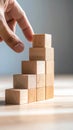 Hand stacking wooden blocks to create an ascending structure representing business growth development strategy and Royalty Free Stock Photo