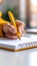 Hand writing with a yellow pen on a notebook Royalty Free Stock Photo