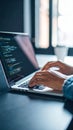 Hands typing on laptop with coding on screen, working in office setting. Royalty Free Stock Photo