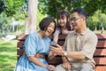 Happy asian family of three having fun watching a phone together in the summer outdoors at the park. Royalty Free Stock Photo