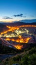 Illuminated Open Pit Mine at Dusk with Equipment and Mountain Landscape Royalty Free Stock Photo