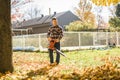 A Man cleaning fallen leaves using a leaf blower on the lawn. Royalty Free Stock Photo