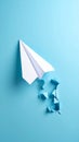 Paper airplane breaking through blue background concept of freedom and travel Royalty Free Stock Photo