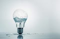 Photorealistic light bulb with water inside standing vertically on the table, puddle around. Ai generated Royalty Free Stock Photo