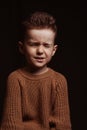 Portrait of frowning serious angry stylish white Caucasian child boy kid preschooler on a chair