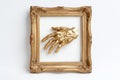 A sculpture of a golden hand displayed in an ornate gold frame on a simple neutral wall, combining classic and contemporary design Royalty Free Stock Photo
