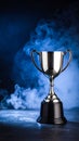 Silver trophy cup against a dramatic blue background with smoke Royalty Free Stock Photo