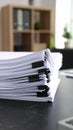 Stack of white paper documents on a desk with black binder clips in an office setting Royalty Free Stock Photo