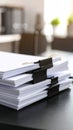 Stack of white paper documents held together with black binder clips on a dark desk Royalty Free Stock Photo