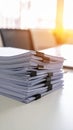 Stack of white paper documents held together with black binder clips on a white desk. Royalty Free Stock Photo
