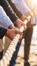 Teamwork hands pulling thick rope together in bright sunlight for business collaboration and strength Royalty Free Stock Photo