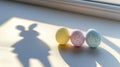 Three colorful Easter eggs beside the shadow of a rabbit create a festive spring scene. Royalty Free Stock Photo