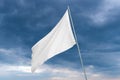 A white flag waves in the wind with dark clouds in the background Royalty Free Stock Photo
