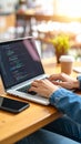 Woman coding on laptop at cafe, hands typing on keyboard, coffee cup and phone on desk Royalty Free Stock Photo