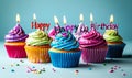 Colorful birthday cupcakes lined up with lit candles spelling Happy Birthday against a soft blue backdrop for festive Royalty Free Stock Photo