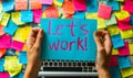 Hands holding a blue sticky note with the phrase lets work! amidst a chaotic background of colorful post-it notes and a Royalty Free Stock Photo