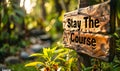 Motivational Stay The Course sign held up with two hands, promoting persistence and dedication, set against a lush green