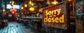 Rustic Sorry were closed sign hanging on a blurry background of a dimly lit bar with warm ambient lighting and vintage Royalty Free Stock Photo