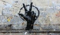 Street art of a black painted hand making a peace sign against a weathered white wall, representing urban expression, peace Royalty Free Stock Photo