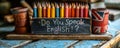 Vintage chalkboard with Do You Speak English? question, British flag, and pencils on rustic wooden backdrop, representing Royalty Free Stock Photo