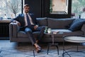 Young and charming businessman is thinking about business while sitting on the sofa in his modern office.