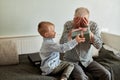 Generation. grandfather and grandson with gift box sitting on couch at home Royalty Free Stock Photo